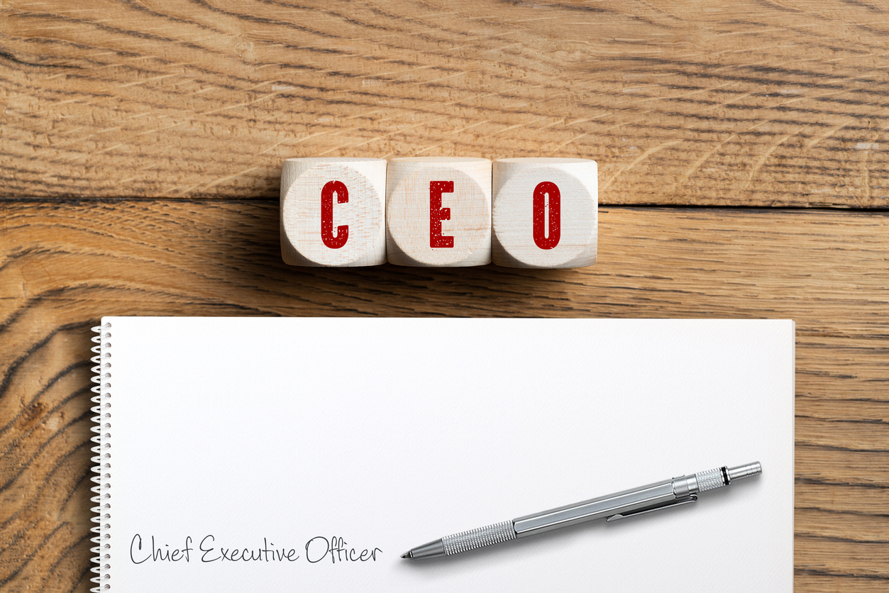 CEO spelled in red on three wooden blocks next to paper with pens on wood surface